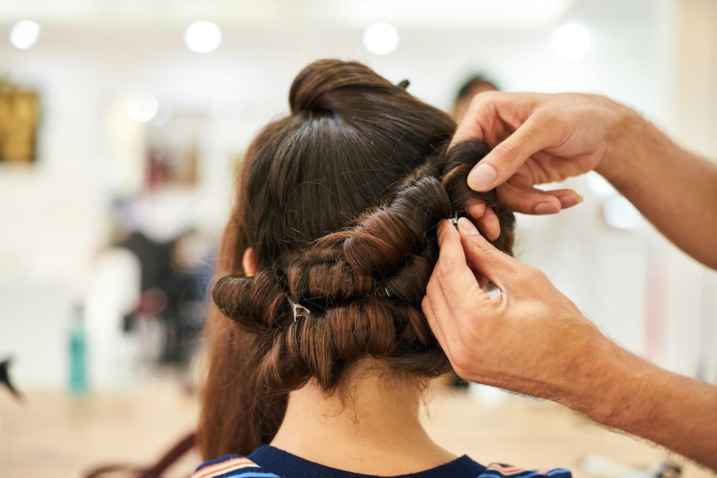 Profissional finalizando penteado com ondas em cabelo castanho