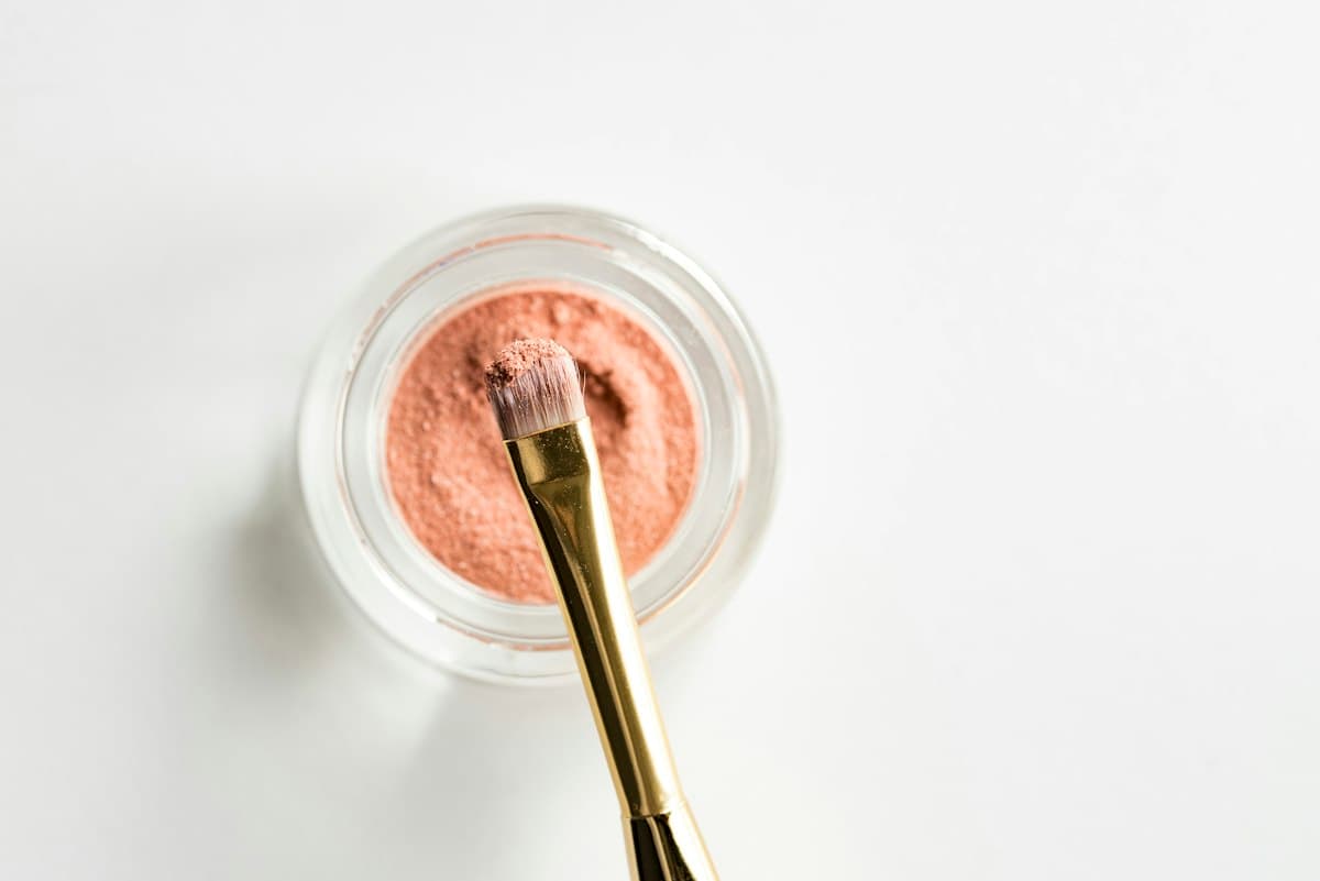 Pincel de maquiagem sobre pote de blush pêssego