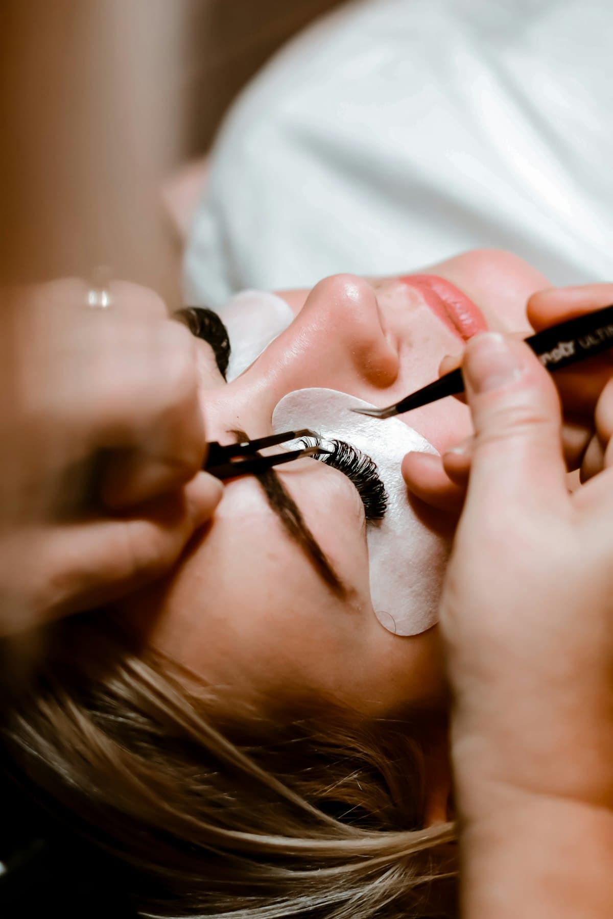 Profissional aplicando extensão de cílios fio a fio