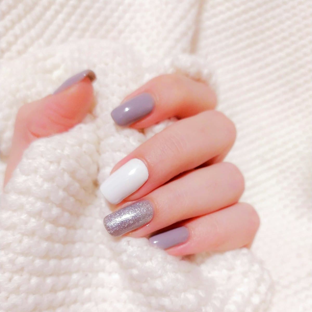 Unhas em tons nude e perolado sobre tricô branco